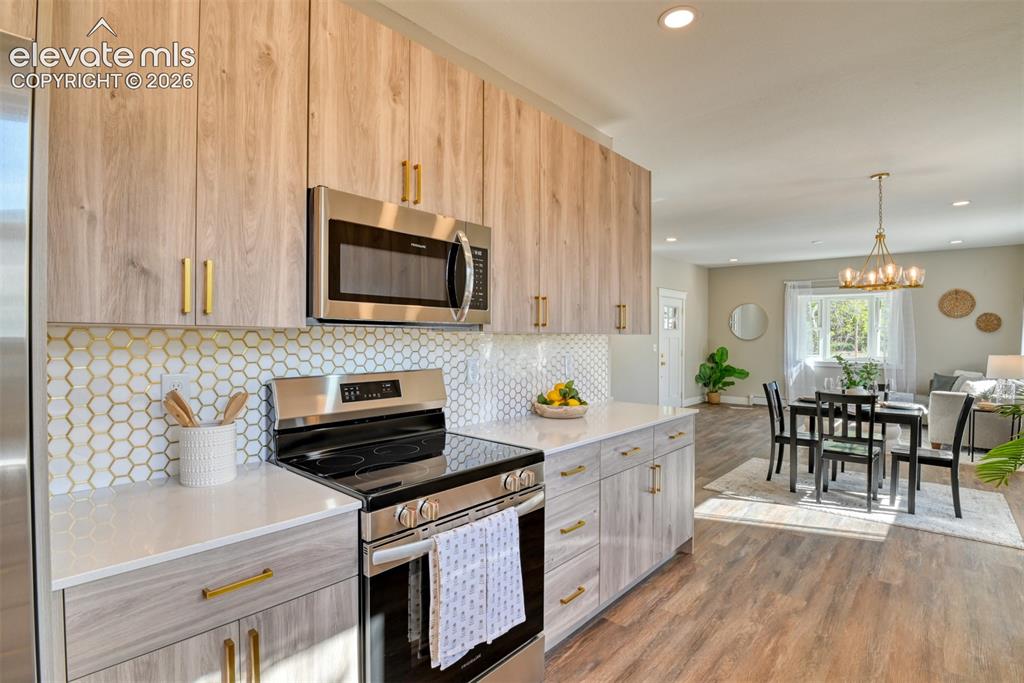 Image 20 of 47: Modern kitchen featuring wood-finish cabinetry with brass hardware, stainle