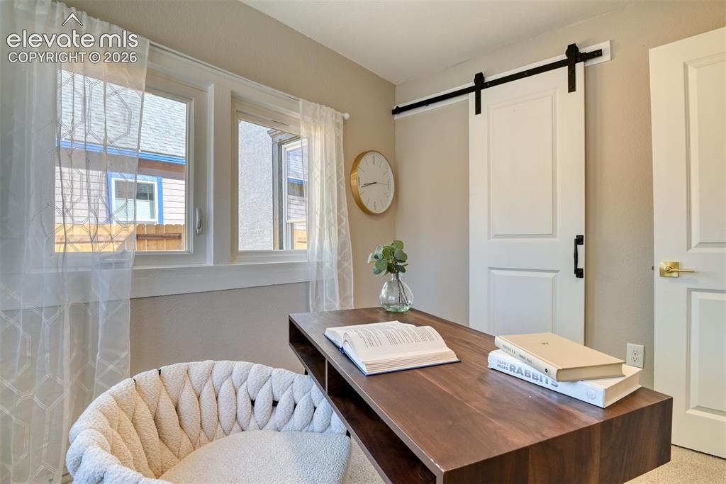 Image 26 of 47: Bright room featuring two windows with white trim, a sliding barn door with