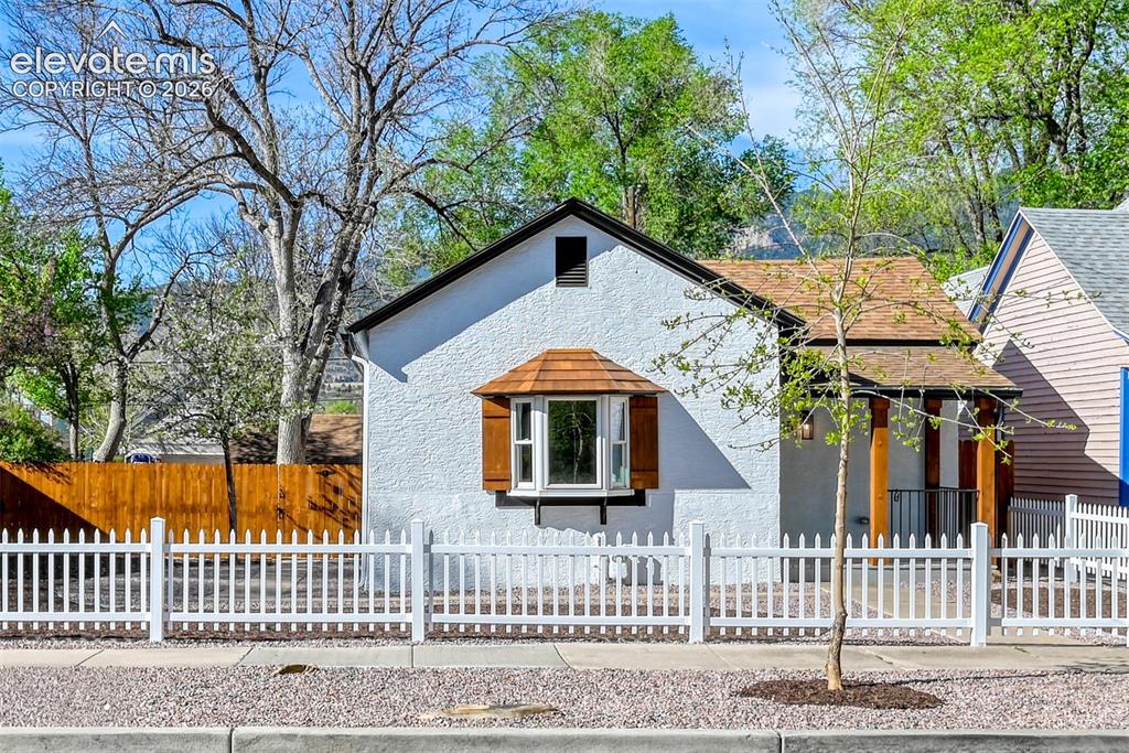 Image 3 of 47: Charming stucco exterior featuring a bay window with a wood-shingled roof a