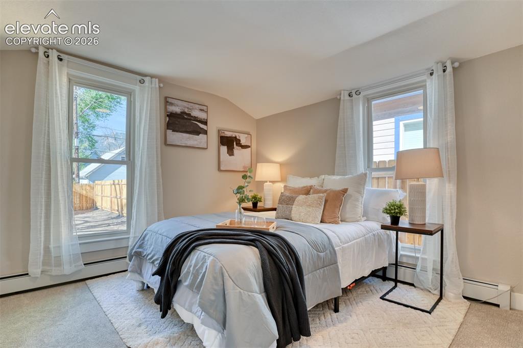 Image 33 of 47: Carpeted bedroom featuring two large windows, neutral wall tones, and baseb
