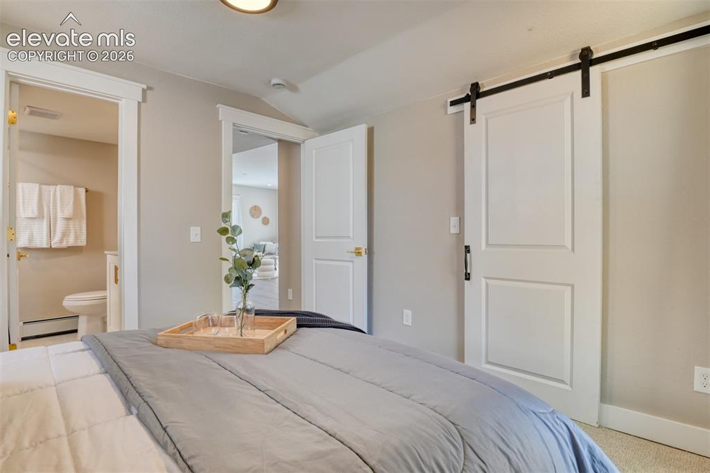 Image 35 of 47: Bedroom featuring a modern barn door, light neutral wall paint, white trim,