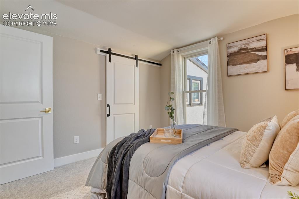 Image 36 of 47: Bedroom featuring a large window with white curtains, light-colored walls, 