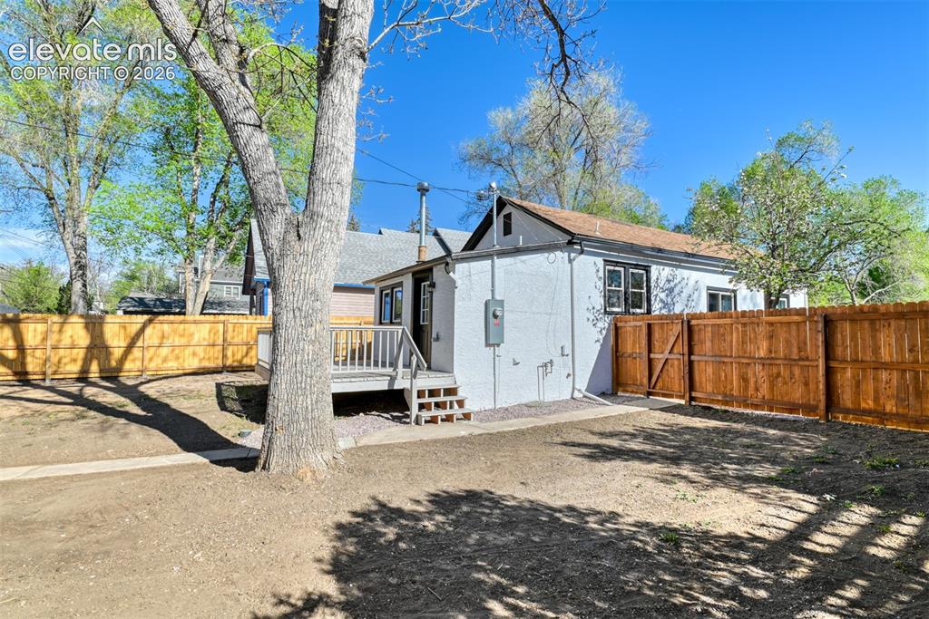 Image 44 of 47: Rear exterior featuring a deck with stairs, a wooden privacy fence, and a m