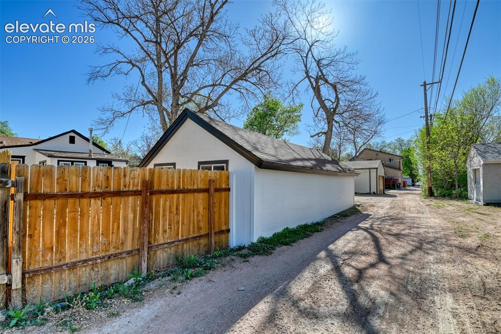 Image 47 of 47: Detached garage with white stucco exterior and black trim, featuring a dark