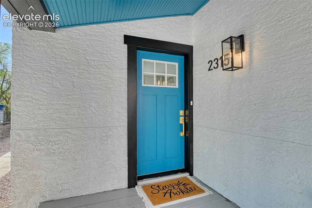 Image 5 of 47: Vibrant blue front door with decorative window inserts, framed by dark trim