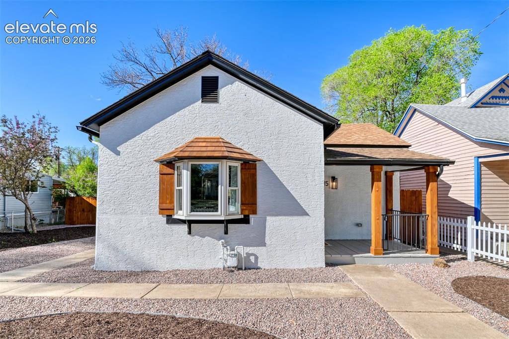 Image 7 of 47: White stucco exterior featuring a bay window with a cedar shake roof and de