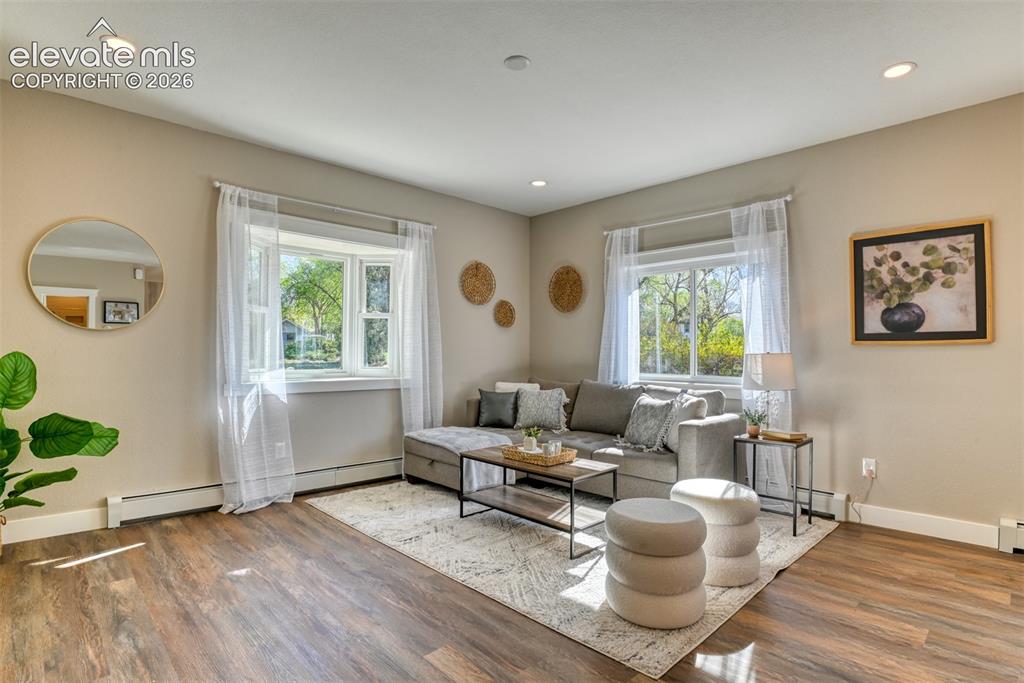 Image 9 of 47: Living area featuring wood-finish flooring, recessed lighting, and bay wind