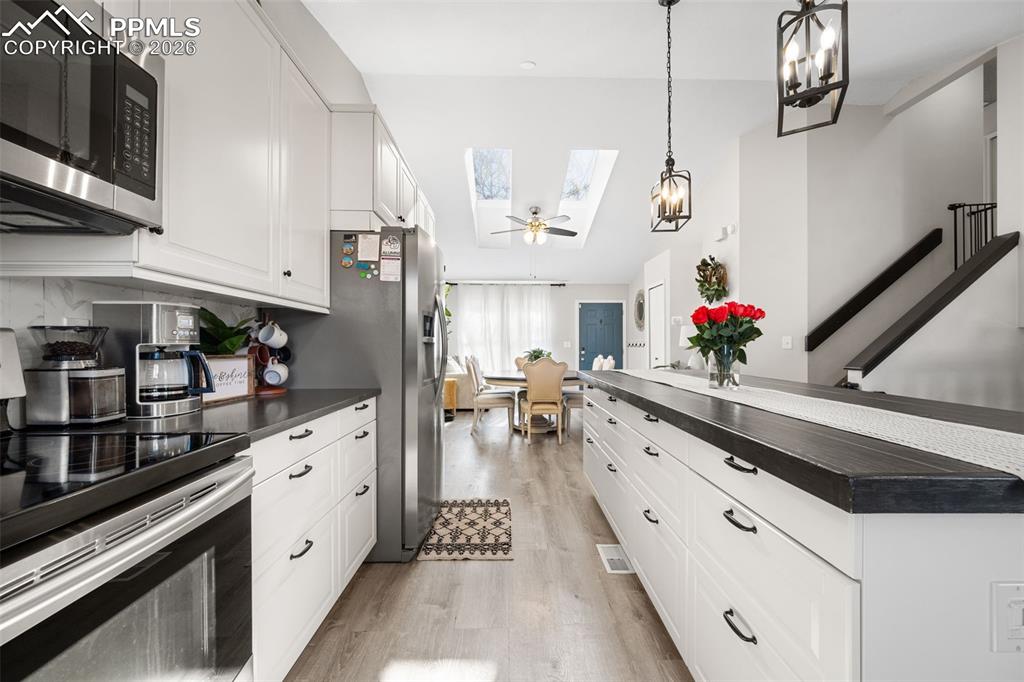 Image 18 of 50: The kitchen features white cabinetry with black hardware, stainless steel a