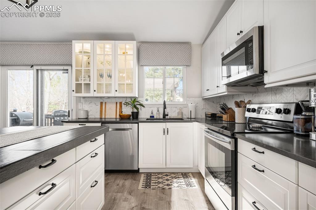 Image 19 of 50: The kitchen features white cabinetry, dark countertops, and stainless steel