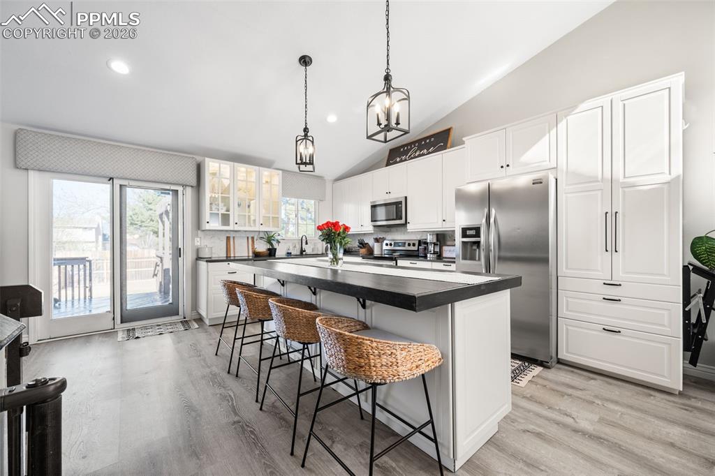 Image 2 of 50: The kitchen features a spacious island with seating, white cabinetry, stain