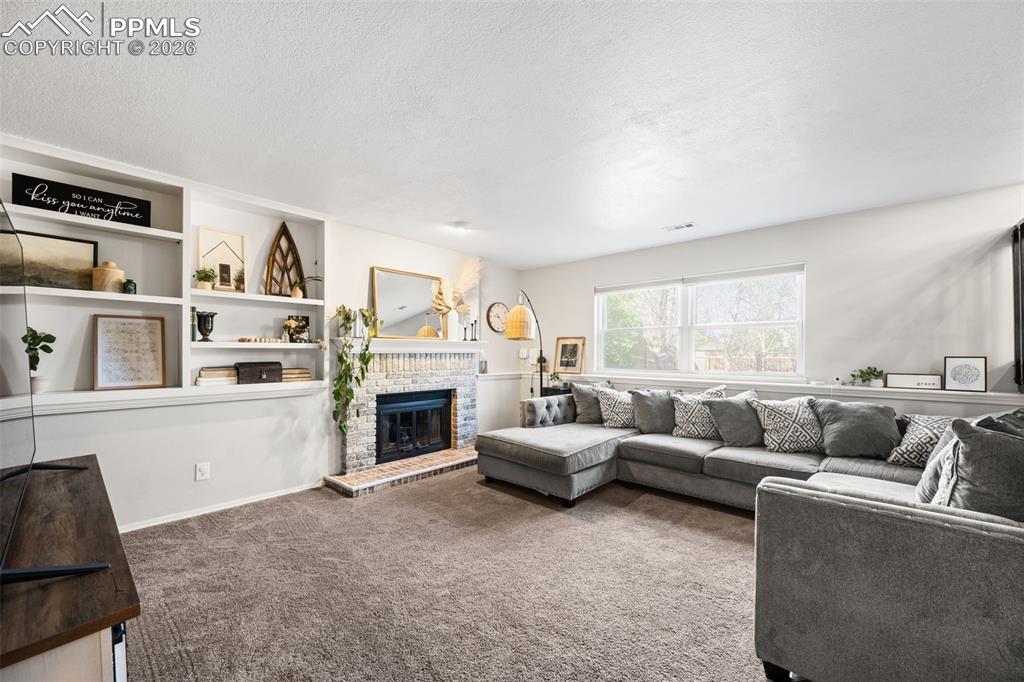 Image 21 of 50: This inviting living space features a cozy fireplace with a stone surround,