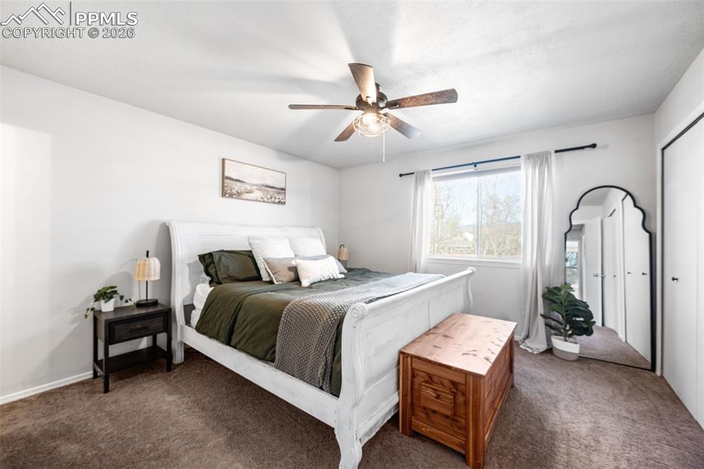 Image 24 of 50: This bedroom features a ceiling fan with integrated lighting, a window with