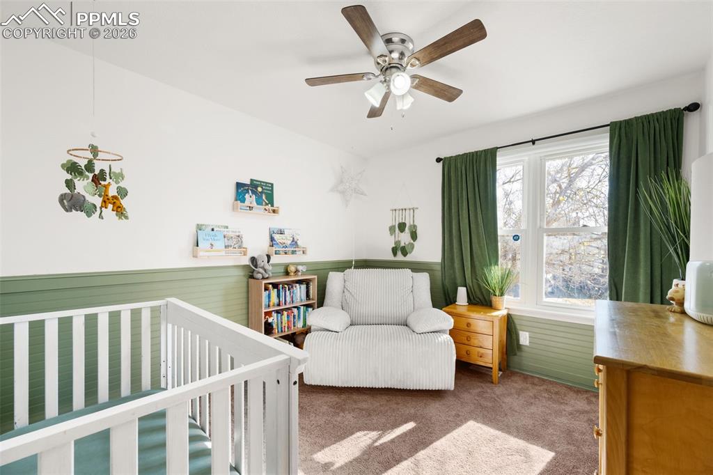 Image 27 of 50: Bedroom featuring a ceiling fan, a window with green curtains, and carpeted