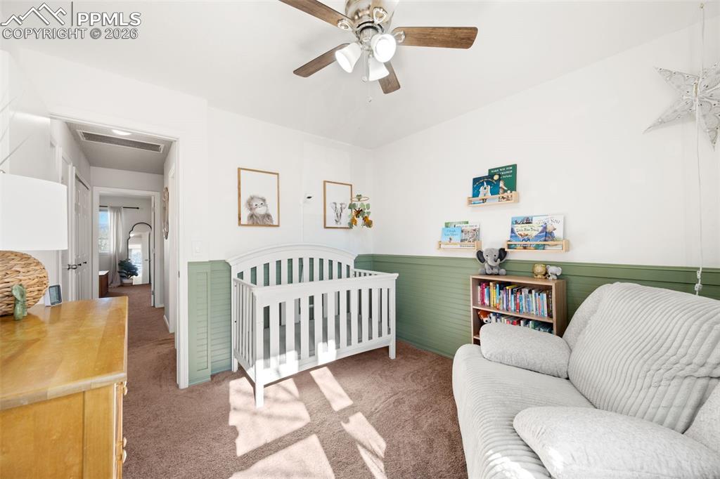 Image 28 of 50: The room features a ceiling fan with light fixture, carpeted flooring, and 