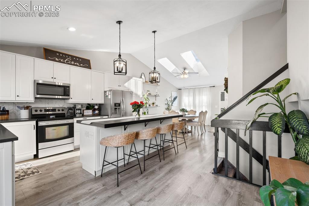 Image 3 of 50: The kitchen features white cabinetry, stainless steel appliances, and a cen