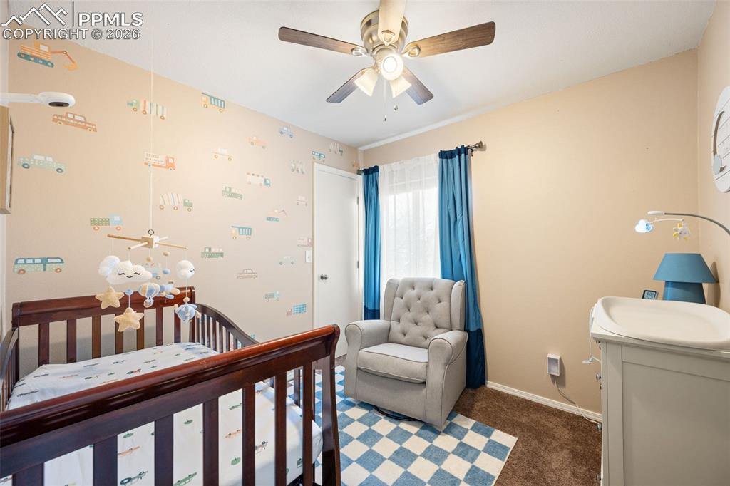 Image 30 of 50: This room features a ceiling fan with integrated lighting, a window with bl