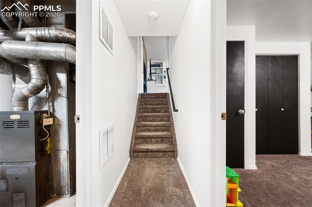 Image 32 of 50: The property features a staircase with carpeted treads and a dark handrail,