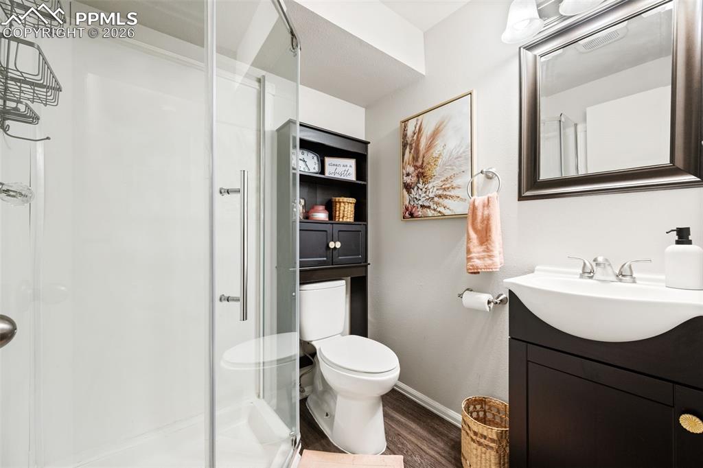 Image 35 of 50: The bathroom features a glass-enclosed shower, a toilet, a vanity with a si