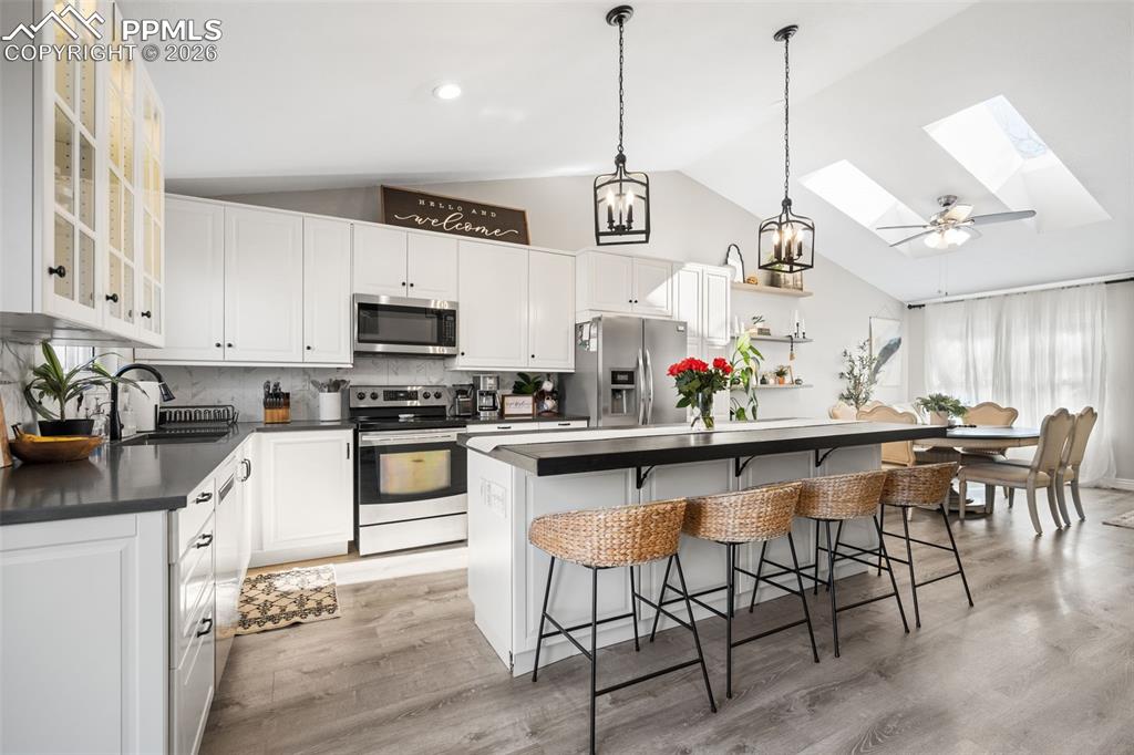 Image 4 of 50: The kitchen features white cabinetry, stainless steel appliances, and a cen