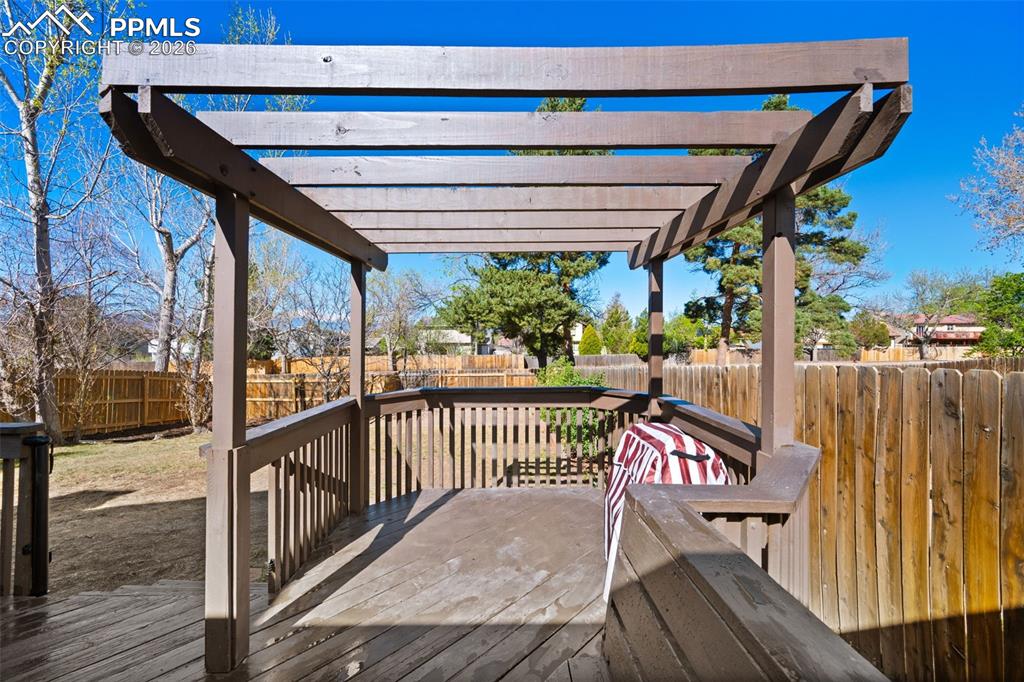 Image 40 of 50: The property features a wooden deck with a pergola, offering an outdoor liv