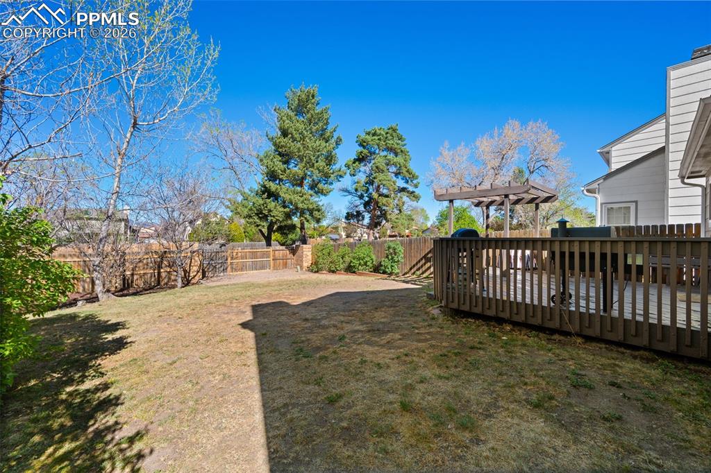Image 41 of 50: The property features an extensive yard with a lawn, a wooden deck, a pergo