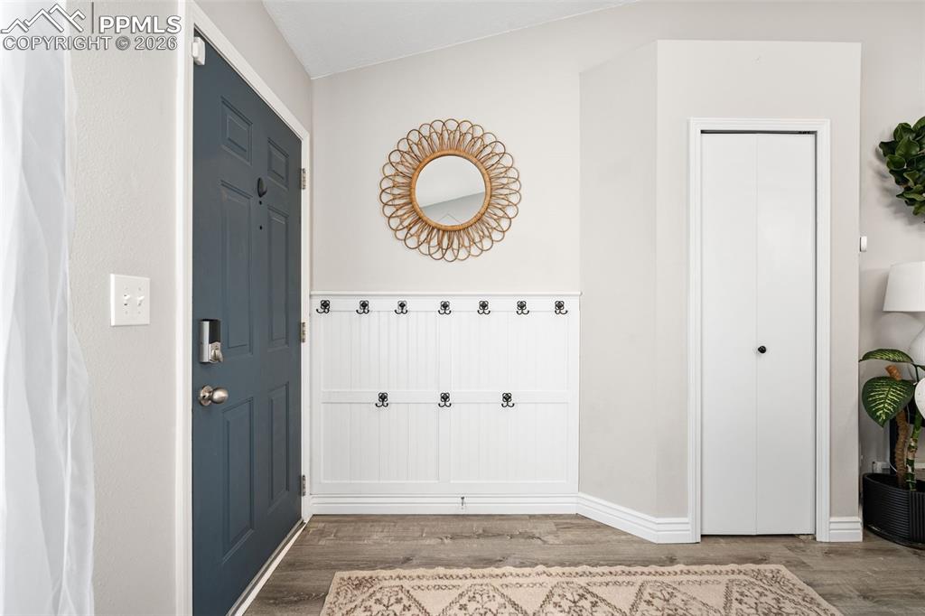Image 6 of 50: Entryway featuring a dark paneled door, a built-in coat rack with hooks, an