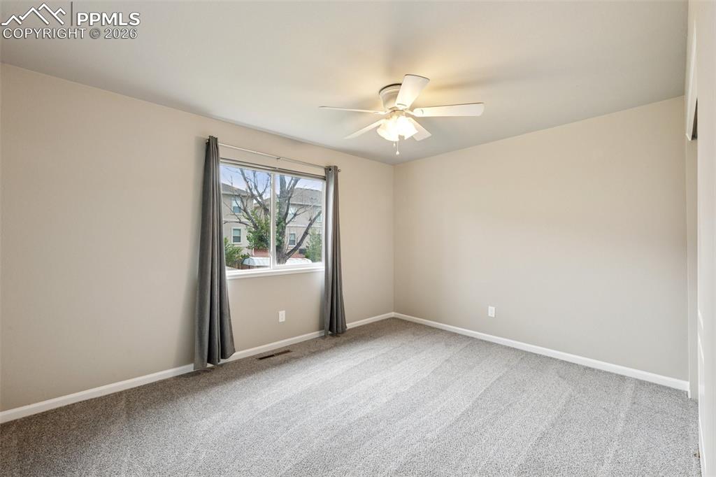 Image 14 of 34: Empty room featuring light colored carpet and a ceiling fan