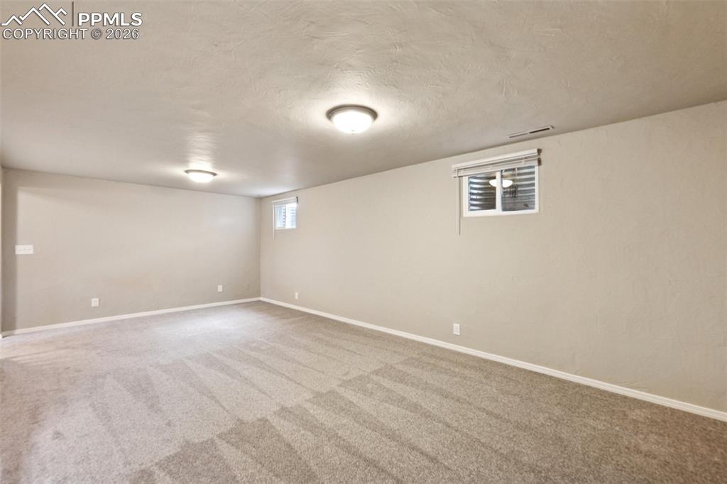 Image 23 of 34: Below grade area with light colored carpet and a textured ceiling