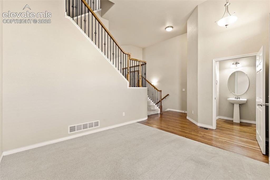 Image 13 of 44: Staircase with wood handrails and wrought iron balusters, light-toned carpe