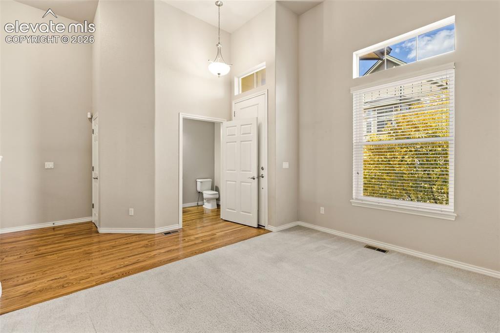 Image 14 of 44: High ceilings with a pendant light fixture, distinct carpet and wood-finish