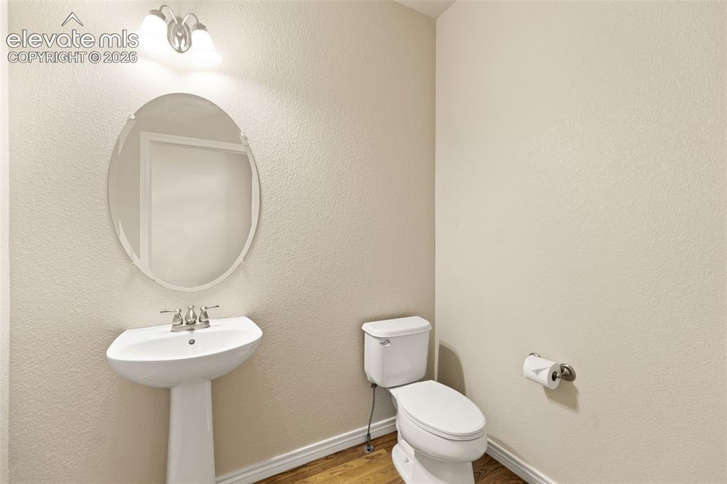 Image 15 of 44: Powder room featuring a pedestal sink with chrome fixtures, oval mirror wit