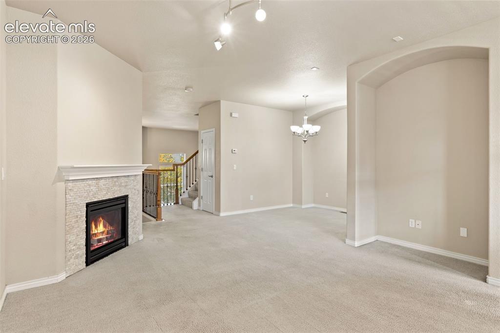 Image 23 of 44: Spacious open-concept living area featuring neutral carpeting, soaring vaul