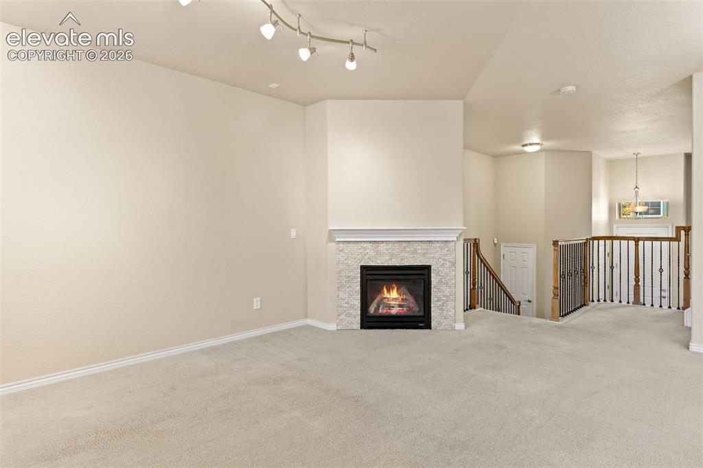 Image 24 of 44: Living area featuring a gas fireplace with a light-toned stone tile surroun