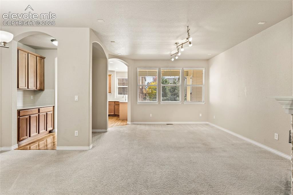 Image 25 of 44: Light-colored carpeting throughout, multiple arched doorways, track lightin