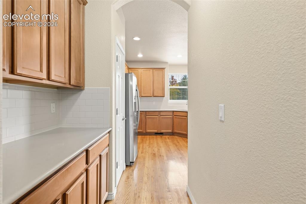 Image 26 of 44: Wood-finish cabinetry, light-toned countertops, and a subway tile backsplas