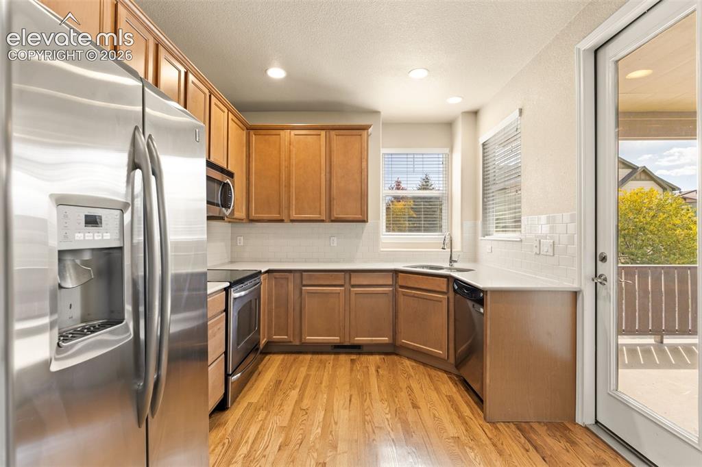 Image 28 of 44: Kitchen featuring wood-finish flooring, stainless steel appliances, wood ca