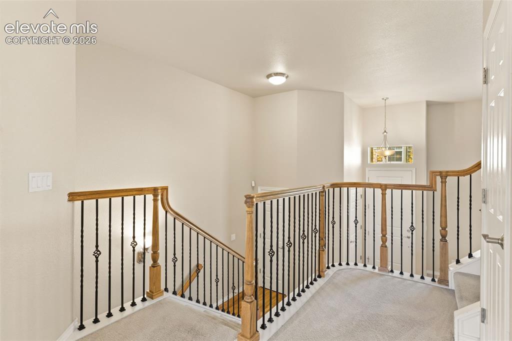 Image 30 of 44: Carpeted landing with wood banister and wrought iron balusters