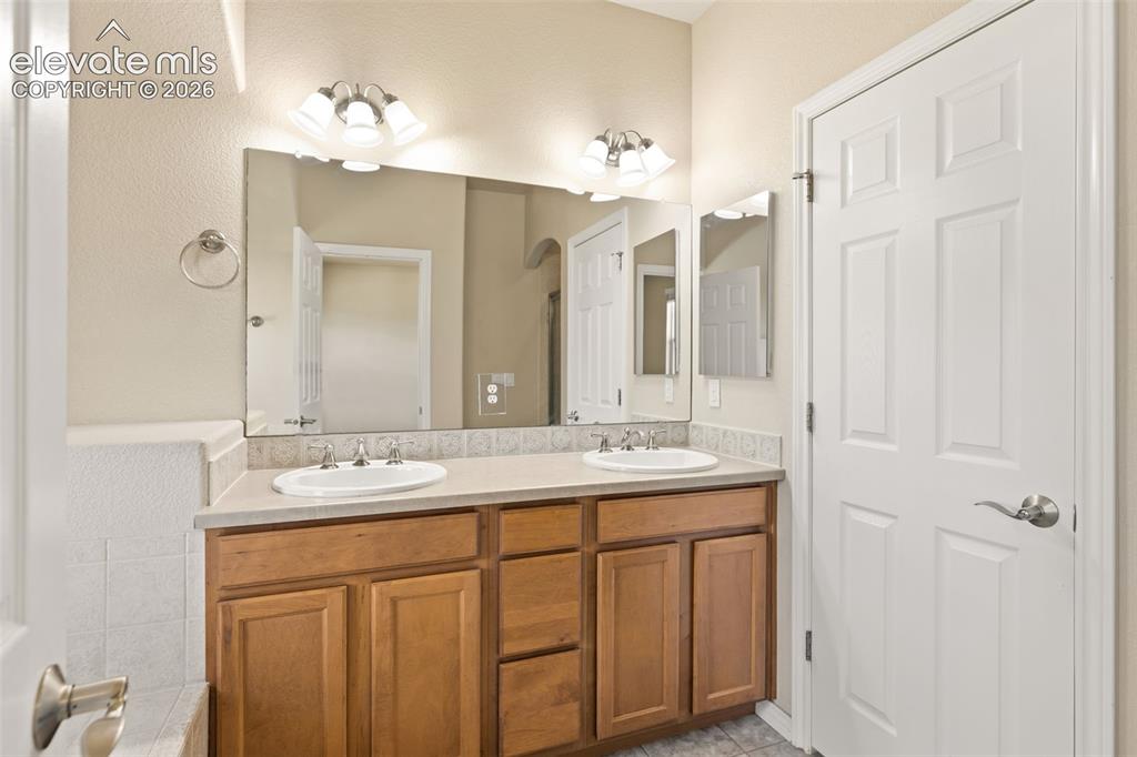 Image 35 of 44: Dual vanity with integrated sinks, wood-finish cabinetry, neutral counterto
