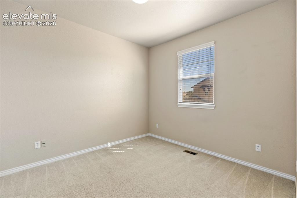 Image 38 of 44: Neutral-toned walls, plush carpeting, and a window with blinds provide a co