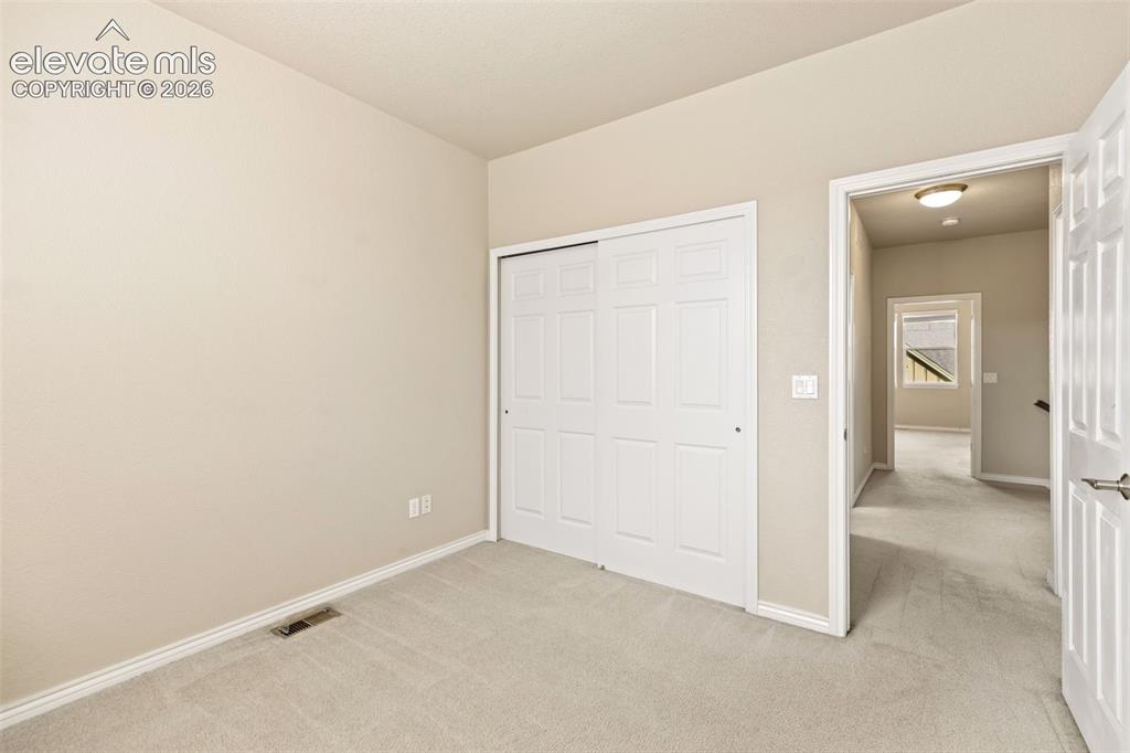 Image 43 of 44: Neutral-toned carpeting, white baseboards, and a bi-fold closet door