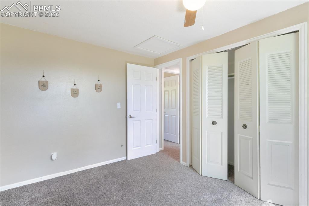 Image 14 of 29: Unfurnished bedroom featuring carpet flooring, attic access, a closet, and