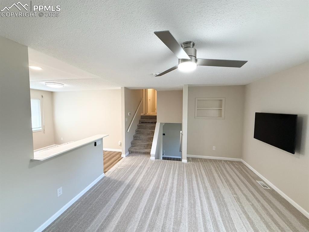 Image 11 of 32: light colored carpet, a ceiling fan, and built in features