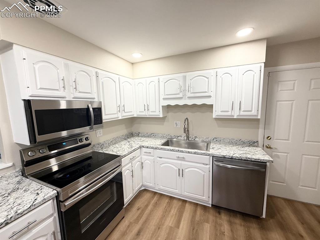 Image 6 of 32: Kitchen featuring appliances with stainless steel finishes, white cabinets,