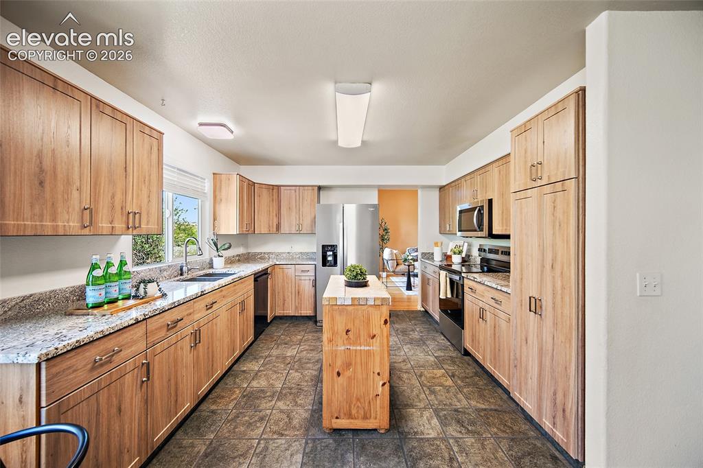 Image 14 of 45: Kitchen featuring wood-finish cabinetry, granite countertops, stainless ste