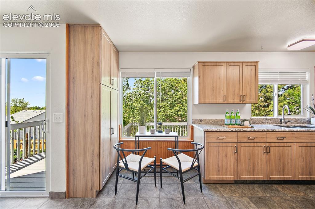 Image 16 of 45: Kitchen featuring light wood-finish cabinetry, speckled granite countertops