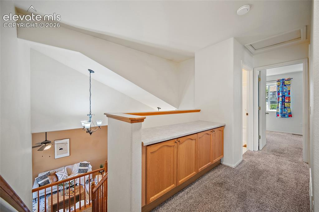Image 20 of 45: Upper-level hallway featuring a built-in wood-finish cabinet with a light-t