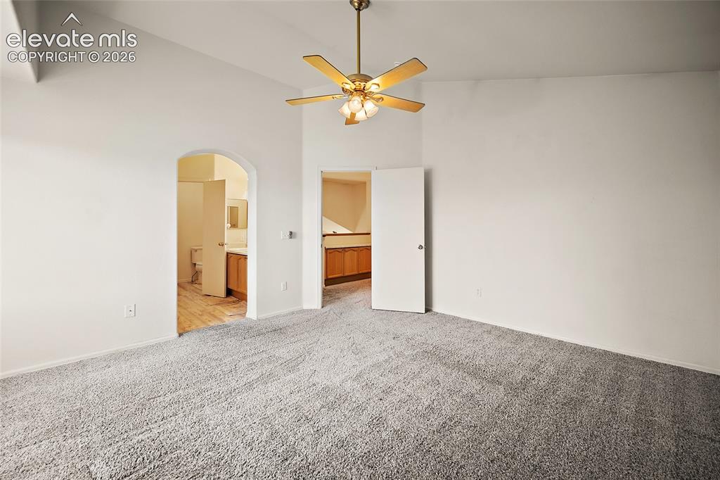 Image 23 of 45: Spacious room featuring vaulted ceilings, a brass-finish ceiling fan with i