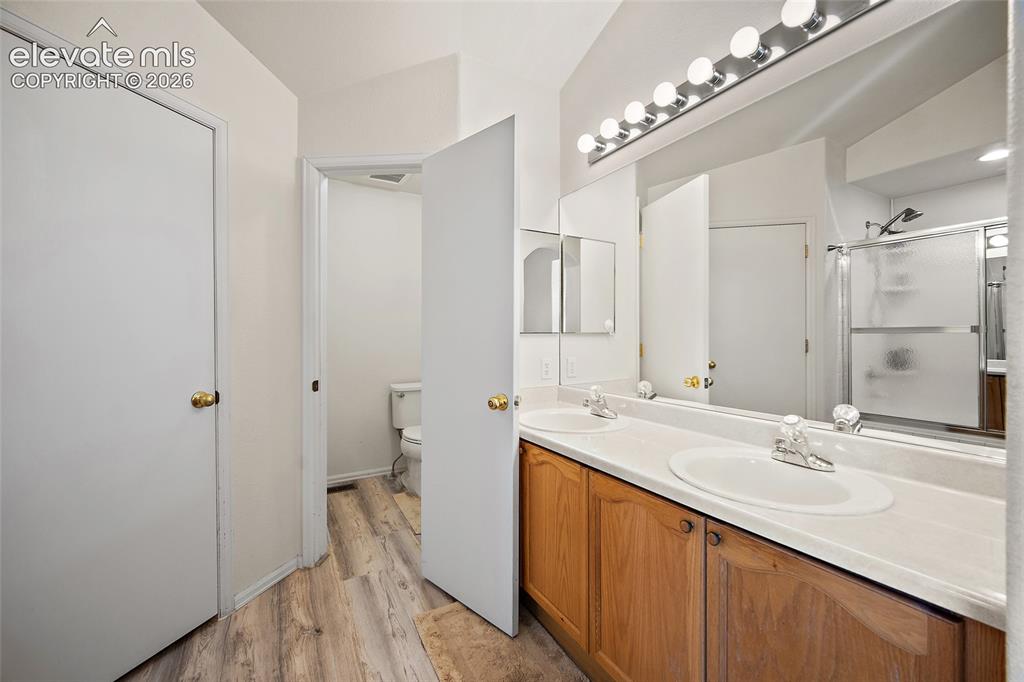 Image 24 of 45: Bathroom featuring a double vanity with wood-finish cabinetry, dual undermo