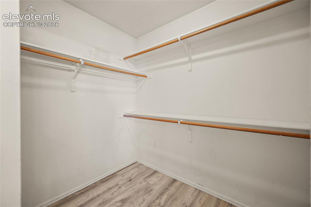 Image 25 of 45: Spacious closet featuring white walls, multi-level shelving, wood-finish fl