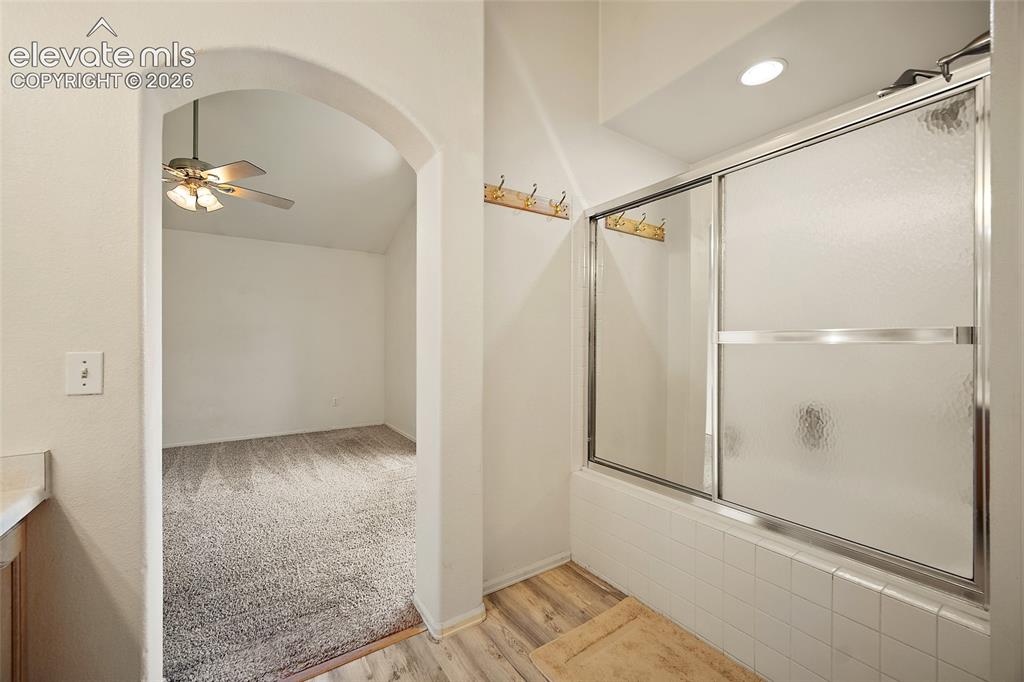 Image 26 of 45: Bathroom with a white tiled shower/tub combination featuring a sliding glas